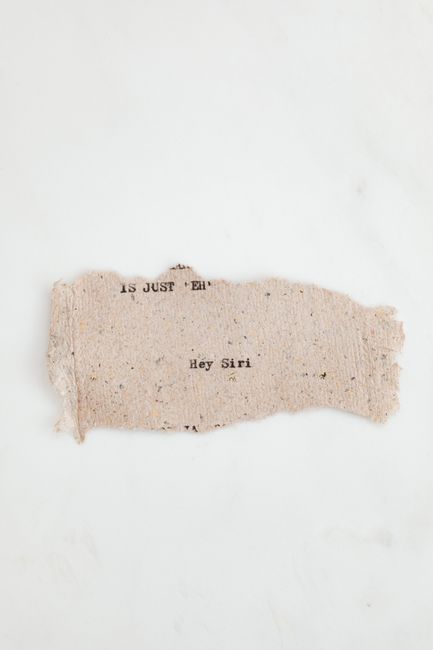A close-up of vintage paper with typewriter text reading 'Hey Siri' on a white background.