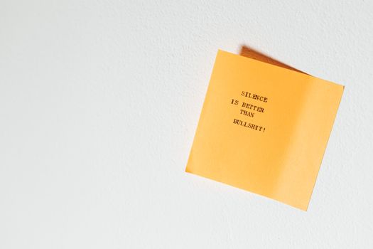Yellow sticky note with motivational quote 'Silence is better than bullshit!' against white background.