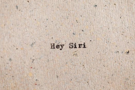 Close-up view of 'Hey Siri' text printed on recycled paper, conceptual art.