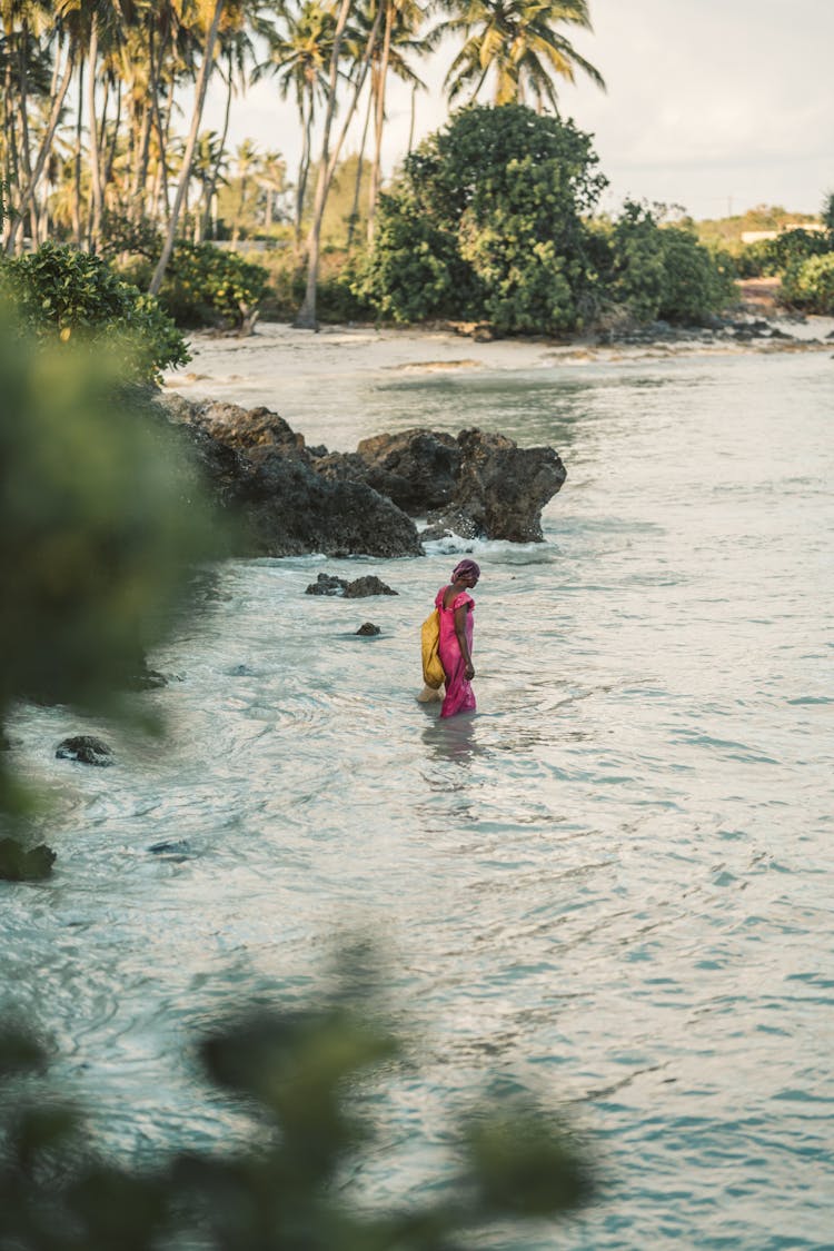 A Woman In A Pink Dress Walking Near Rock Formations