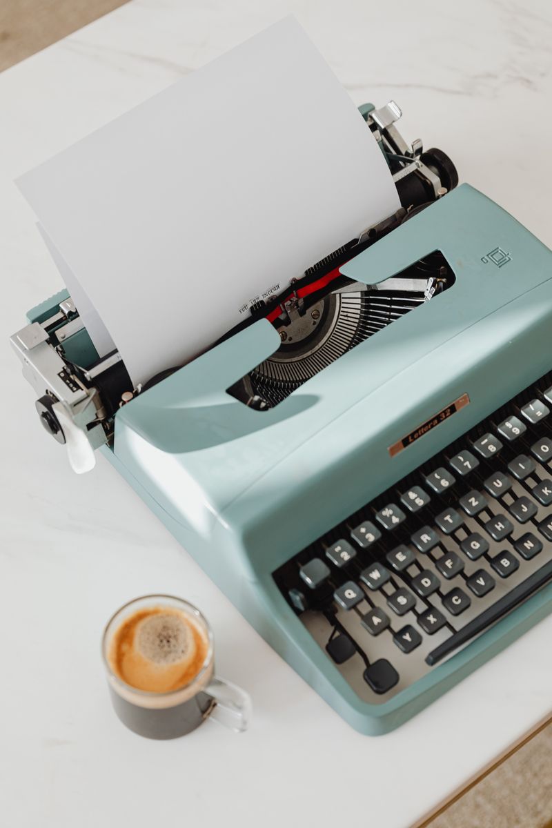 Typewriter with a blank page and a coffee