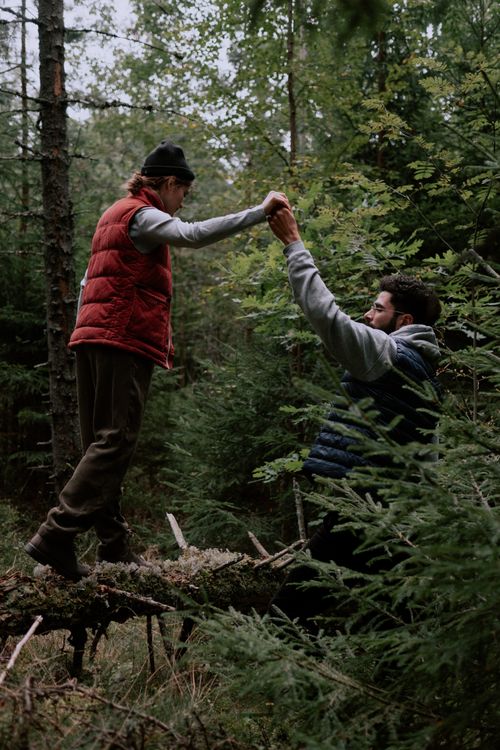 Free A couple assists each other in a lush forest, symbolizing teamwork and adventure. Stock Photo