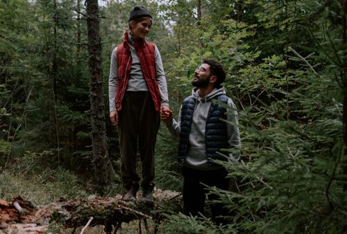 Free A couple holds hands while hiking through a lush forest. Adventure and connection. Stock Photo