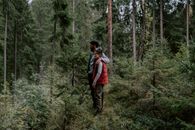 Woman in Blue Jacket and Brown Pants Standing on Forest
