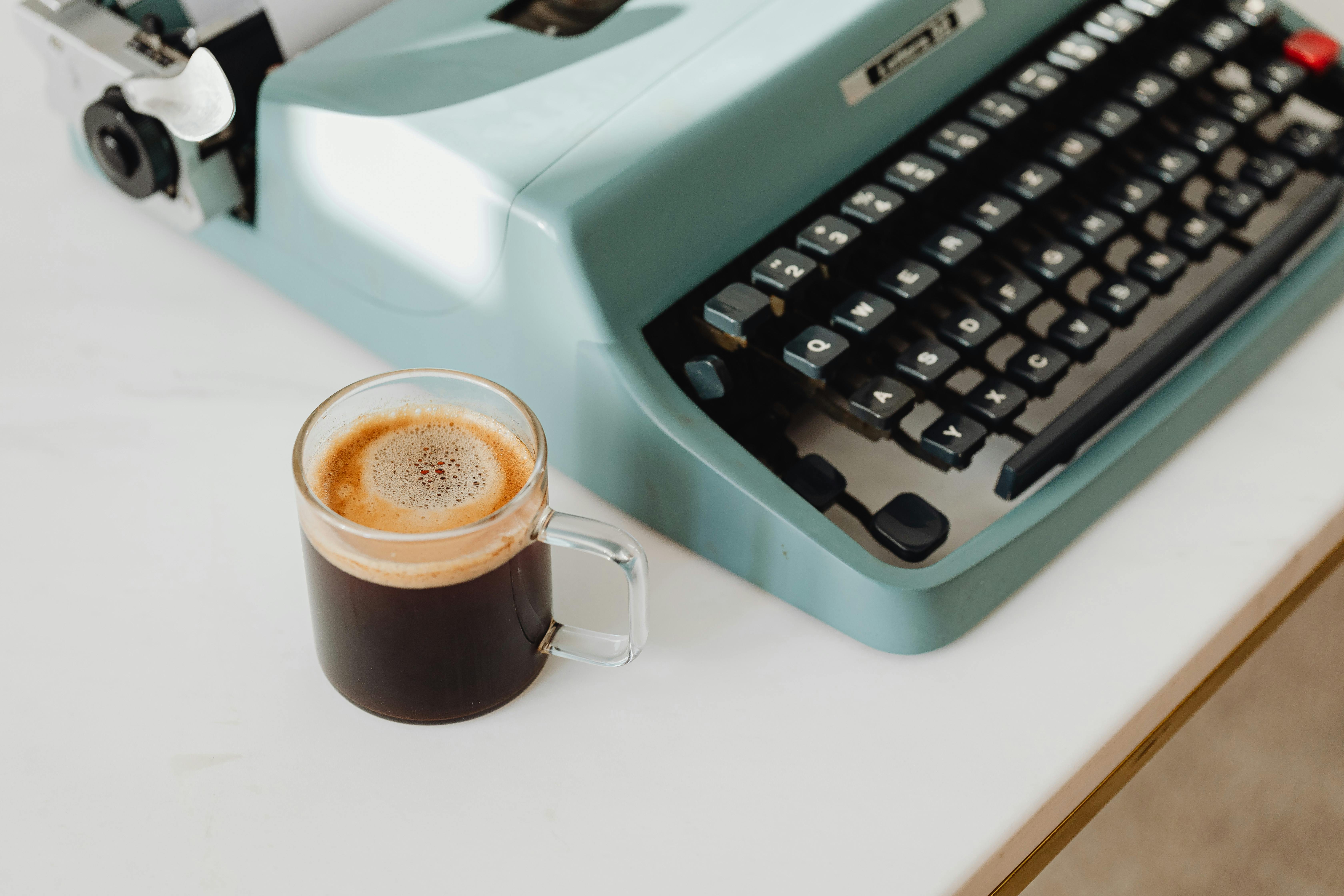 cup of coffee beside a typewriter