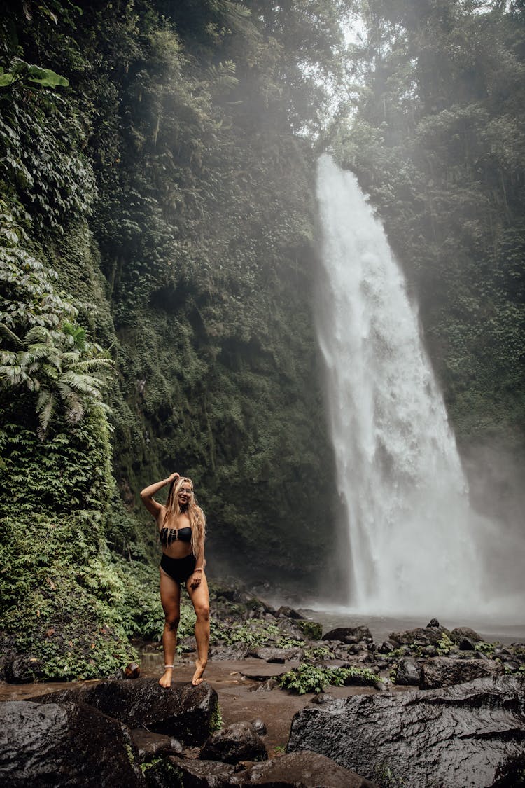 A Woman In Black Bikini Standing Near Waterfalls