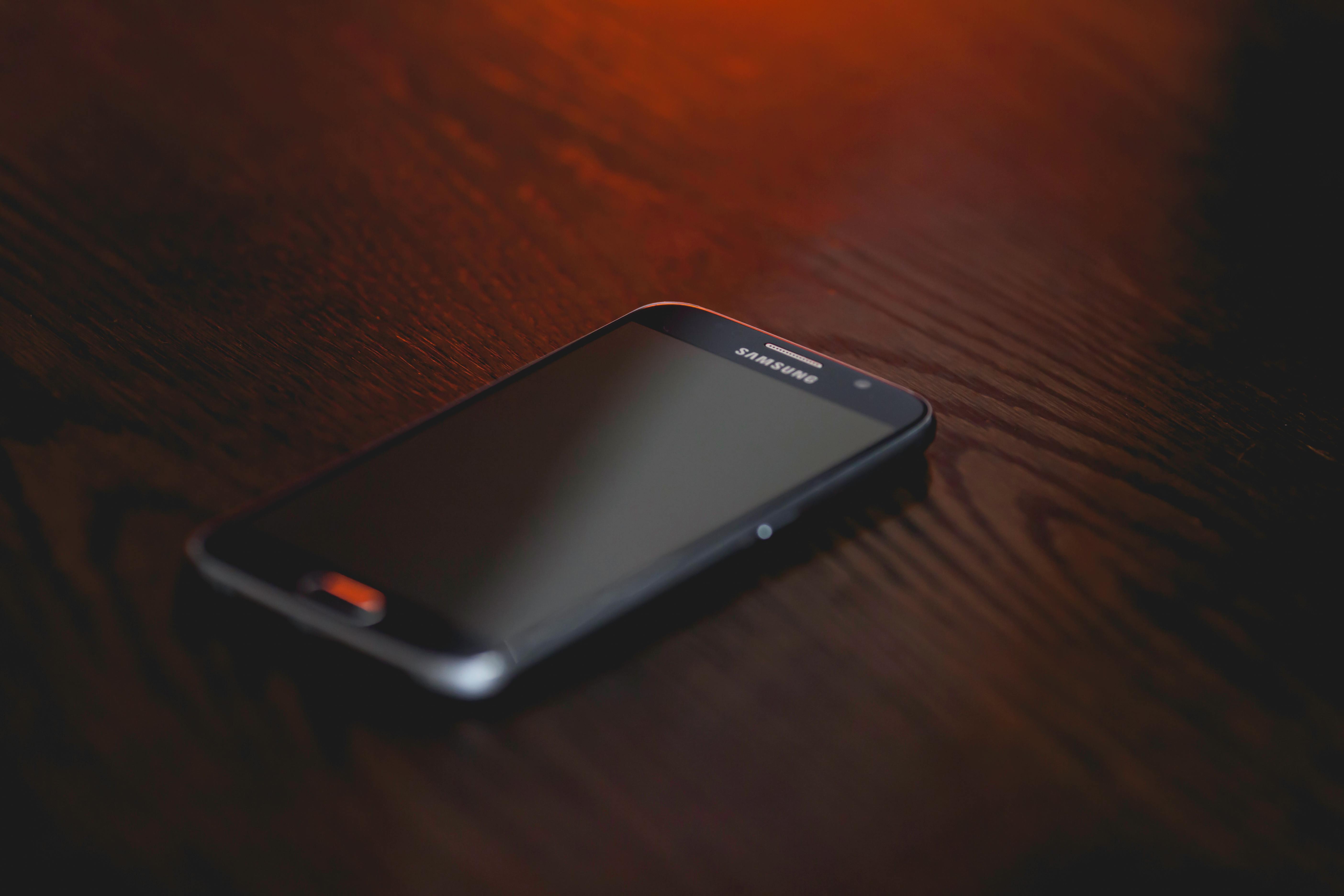 Black Samsung Smartphone at Brown Wooden Surface · Free Stock Photo