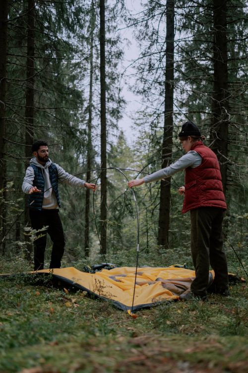 Free Two adults setting up a camping tent in a forest, highlighting outdoor leisure. Stock Photo