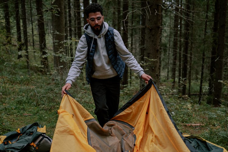 Man In Blue Gilet Setting Up A Tent