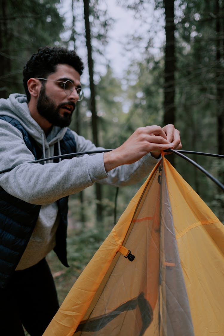 Man In Gray Hoodie Setting Up A Tent