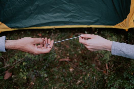 Hands of Persons Holding a Metal Tent Peg
