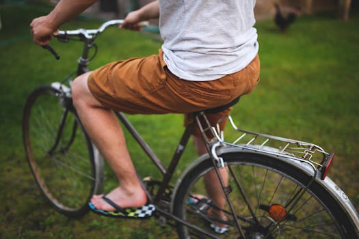 A person riding a bicycle in a park, wearing casual summer clothing and flip-flops.