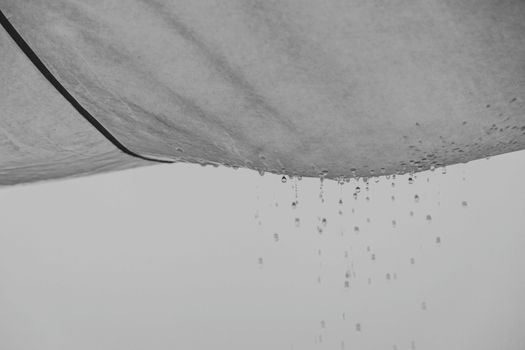 Black and white composition of water drops falling from rag material on gray background