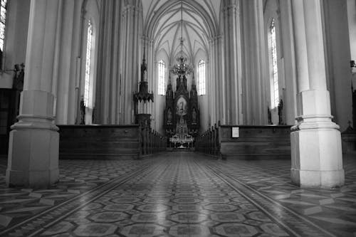 Black and white spacious empty Catholic Church hallway with columns and majestic shrine under arched roof