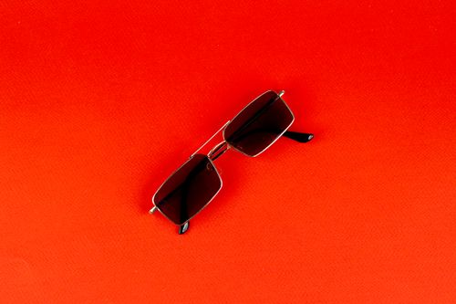 Free Stylish sunglasses resting on a bold orange backdrop making a fashion statement. Stock Photo