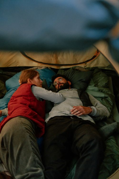 Free A couple comfortably resting together inside a tent during a camping trip. Stock Photo