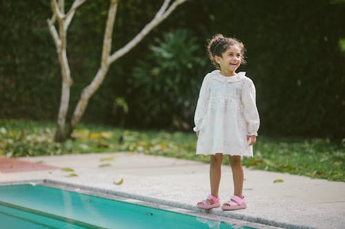 Girl in White Dress Standing on Concrete Floor