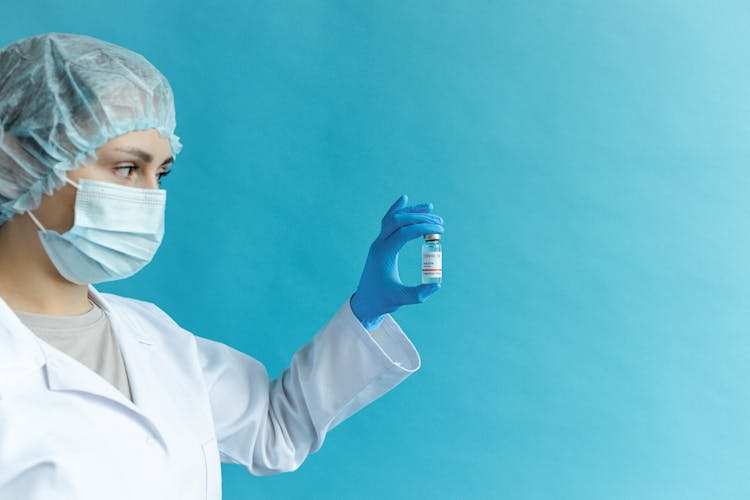 A Woman Wearing Face Mask Holding A Vaccine