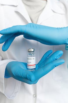 Close-up of a health professional holding a COVID-19 vaccine vial, emphasizing vaccination and health safety.