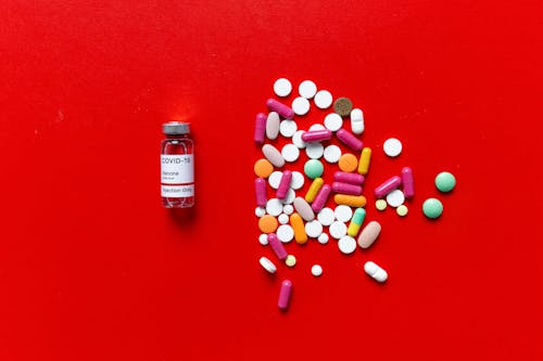 Vial and Pills on a Red Surface