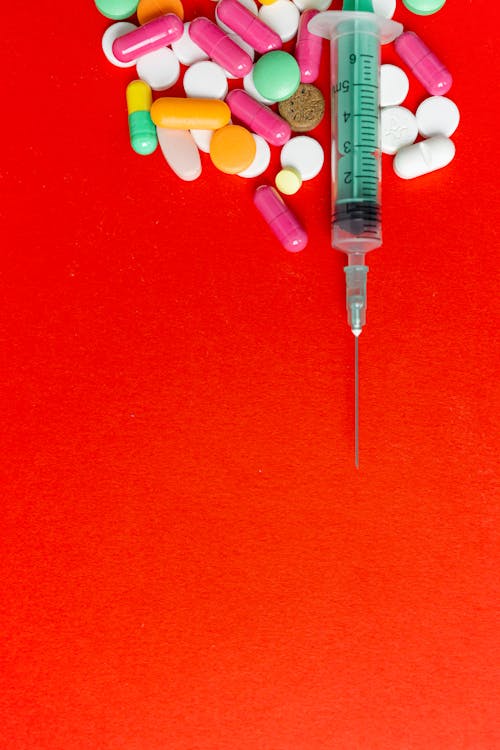 Syringe and Pills on a Red Surface 