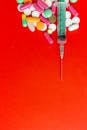Syringe and Pills on a Red Surface