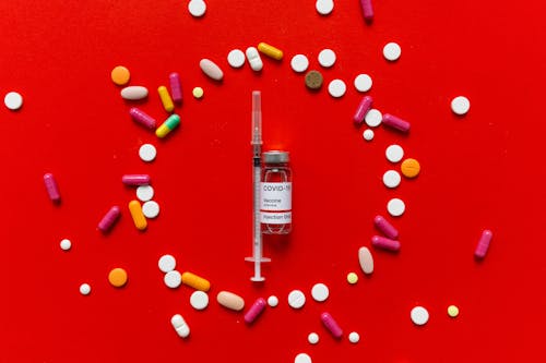A Vial and Syringe Surrounded by Pills 