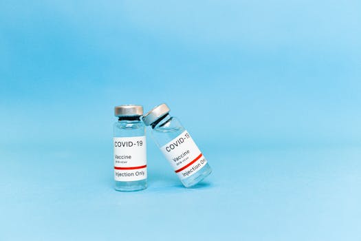 Two COVID-19 vaccine vials labeled for injection on a blue background.