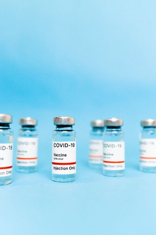 Free Multiple vials of COVID-19 vaccine arranged on a blue background. Stock Photo
