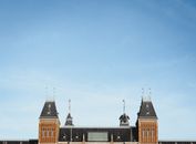 Top of exterior of aged brick building with classic architecture under blue cloudless sky