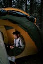 Boy in White Long Sleeve Shirt Sitting on Yellow and Gray Tent