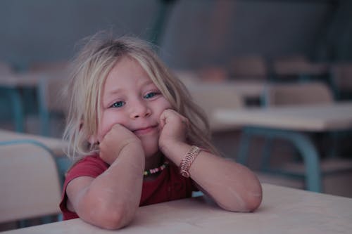 Girl in Red Shirt Leaning on a Table