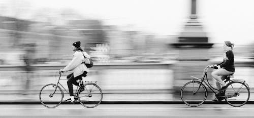 Grayscale Photo of a Man Riding Bicycle