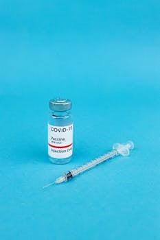 COVID-19 vaccine vial and syringe on blue surface, symbolizing health and protection.