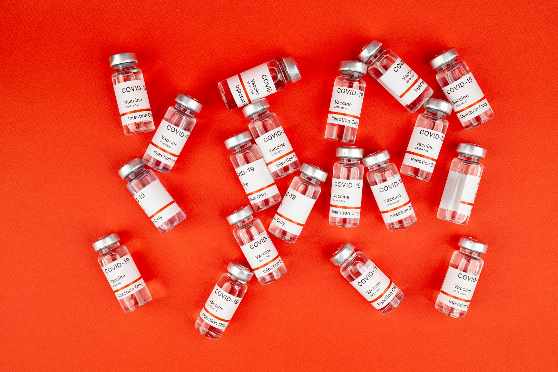 A collection of COVID-19 vaccine vials on a vivid orange background, representing medical advancements.