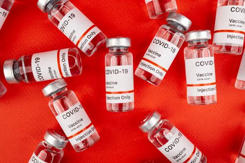 Free Close-up of COVID-19 vaccine vials arranged on a vibrant red background. Stock Photo
