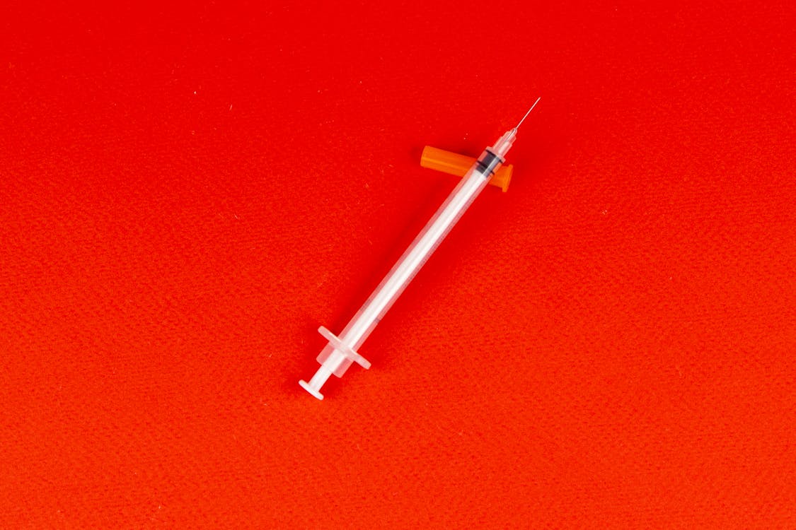 Free Syringe on a Red Surface Stock Photo