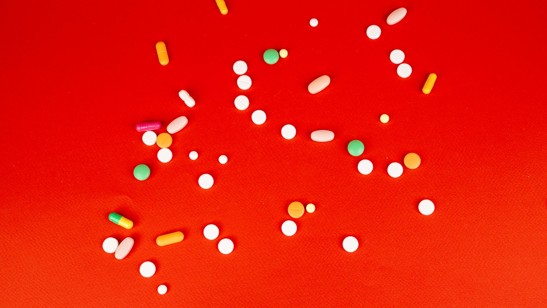 Prescription Nootropics: Enhancing Brain Function A colorful assortment of pills and capsules scattered on a bright red surface. Healthcare and medication concept — prescription nootropics