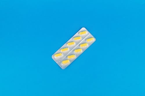 Yellow Medicine Capsules on a Blue Surface