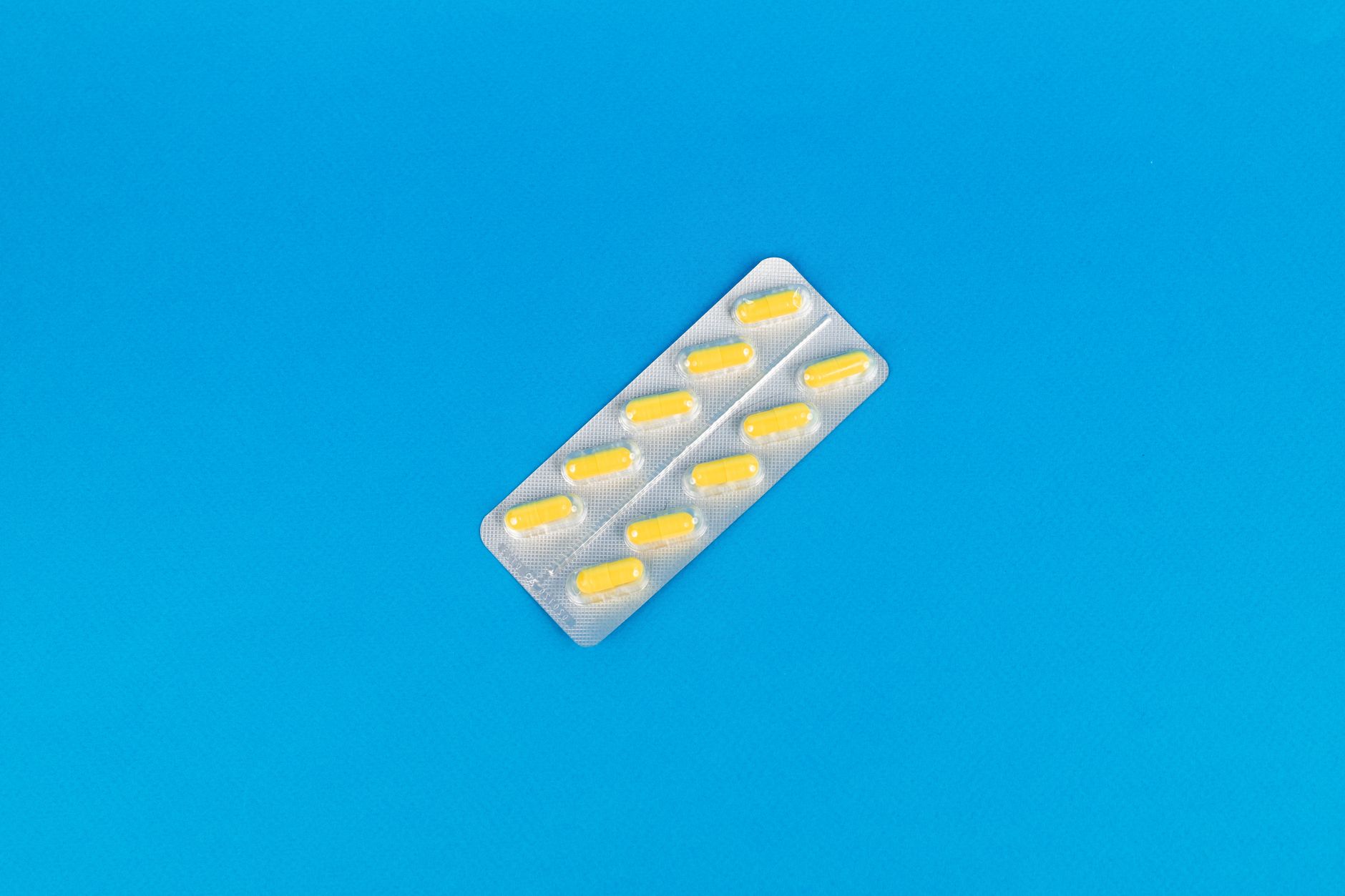 Pack of yellow capsules on a vibrant blue background symbolizing modern medicine.