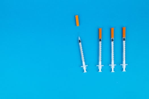 Four medical syringes with orange caps on a vivid blue background, ideal for healthcare or vaccination themes.