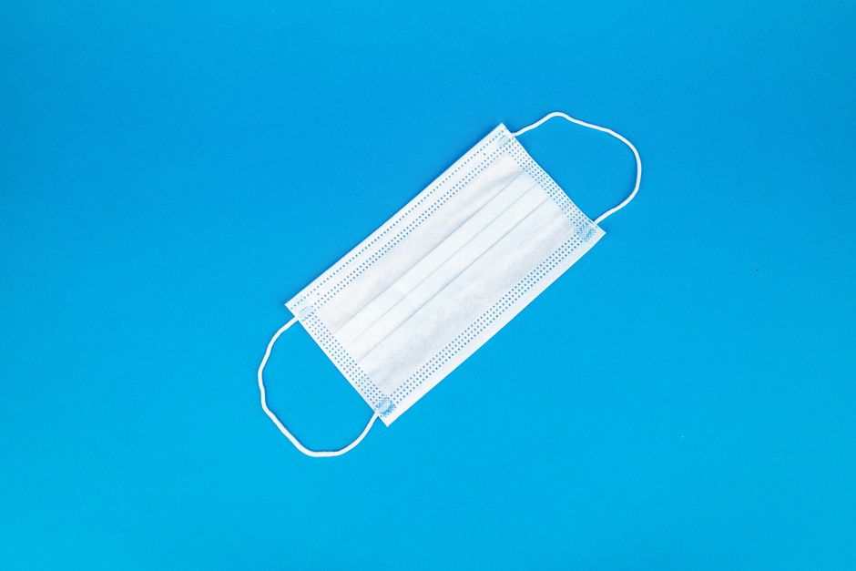 Disposable white face mask on vibrant blue backdrop, symbolizing health protection.