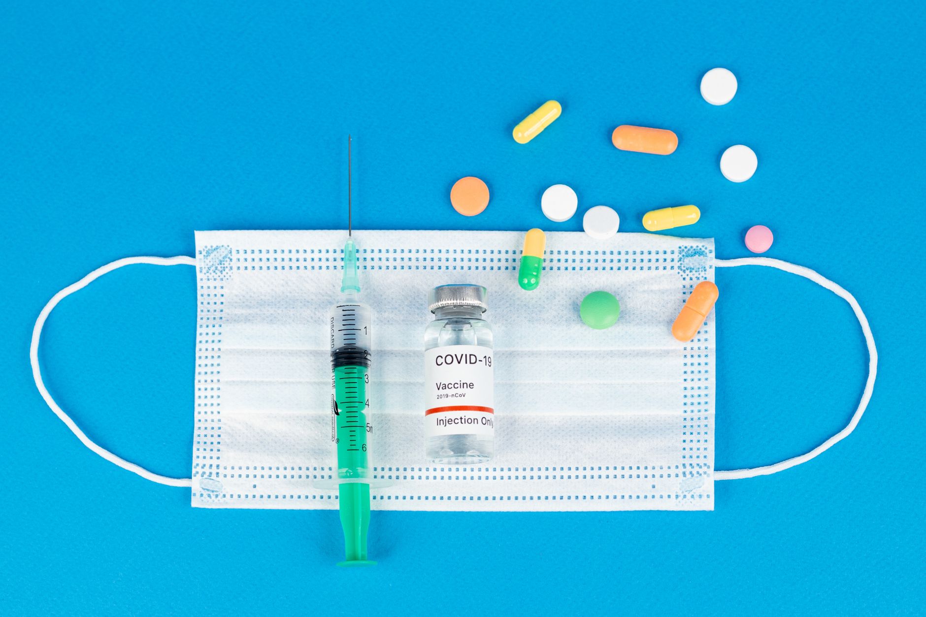 Vaccine, syringe, and face mask symbolize COVID-19 protection against the pandemic.
