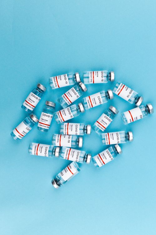 Free Top view of multiple Covid-19 vaccine vials on a blue background emphasizing vaccination effort. Stock Photo