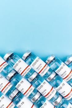 Close-up of COVID-19 vaccine vials arranged diagonally on a blue surface.