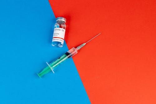 Green Syringe Beside the Vaccine Bottle