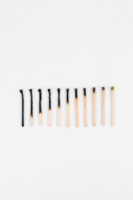 Conceptual image showing evolution of matchsticks from burnt to unlit arranged on white background.