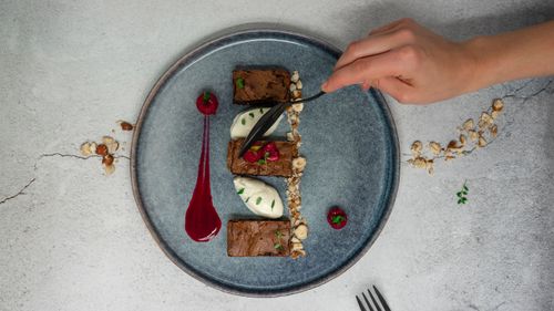 Free Top view of crop anonymous person holding spoon while eating delicious chocolate dessert from ceramic plate Stock Photo