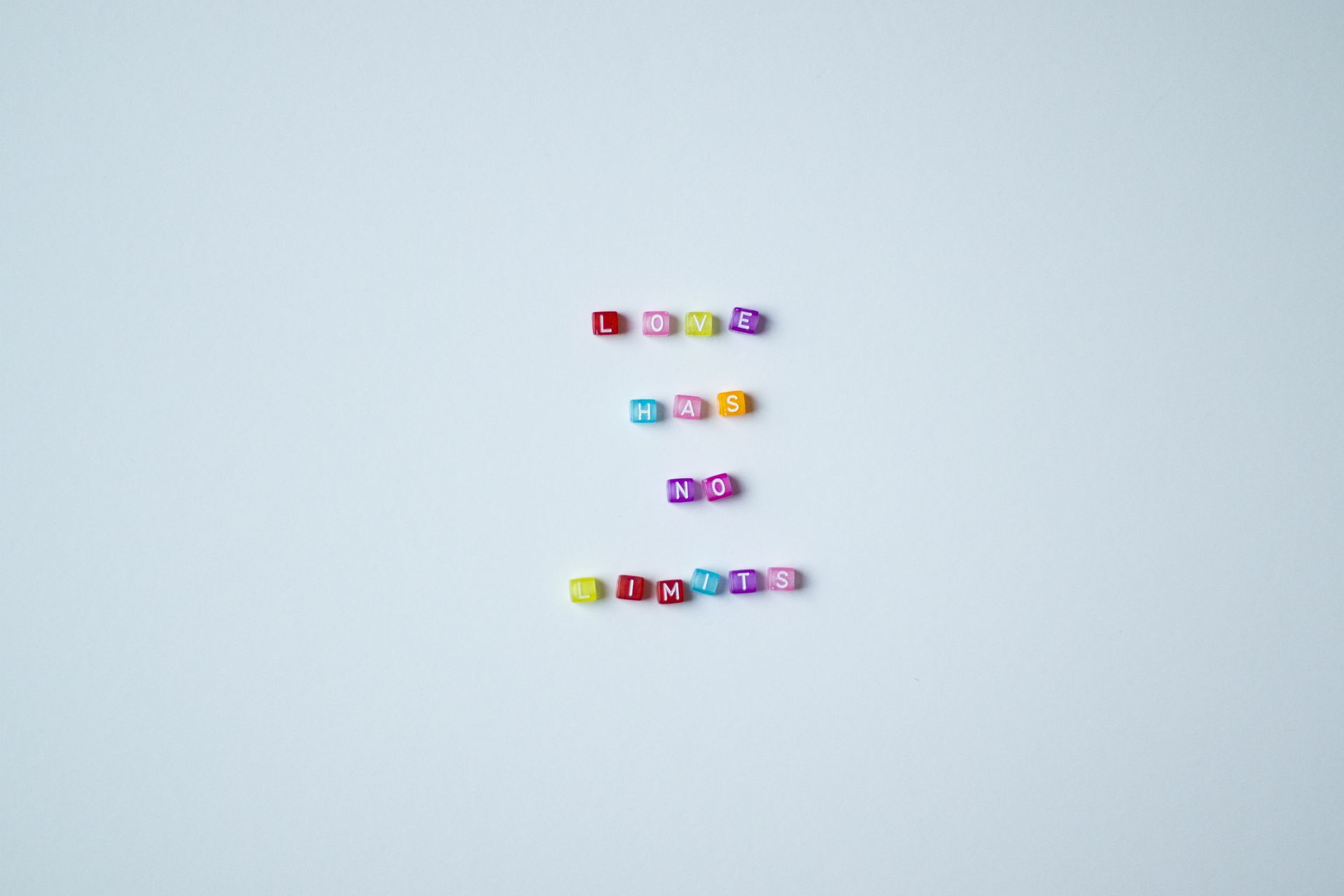 Vibrant bead letters spelling 'Love Has No Limits' on a gray background promoting inclusivity.