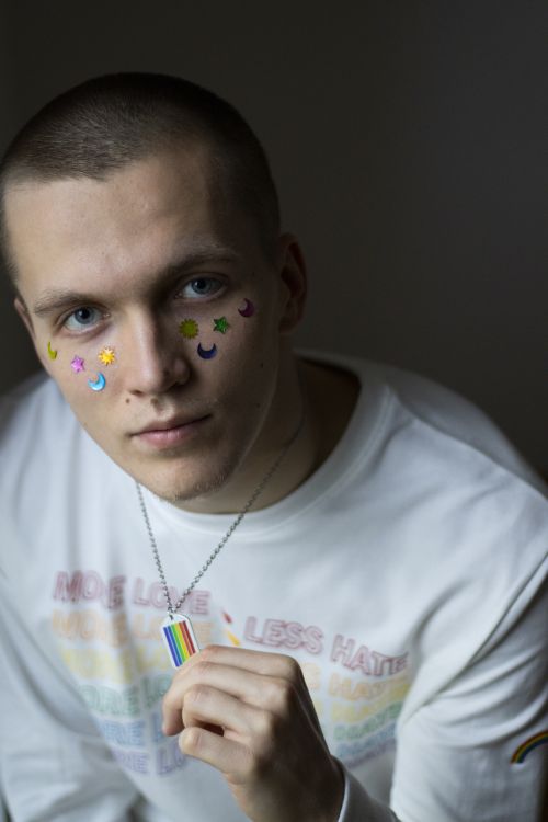 Free A person holding a rainbow necklace, expressing LGBTQ+ pride in a studio setting. Stock Photo